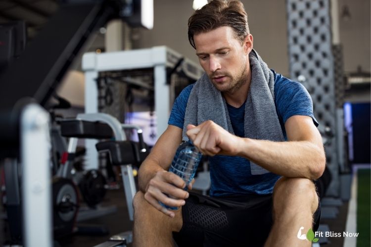 Athlete drinking water during a workout or holding a water bottle with electrolytes.